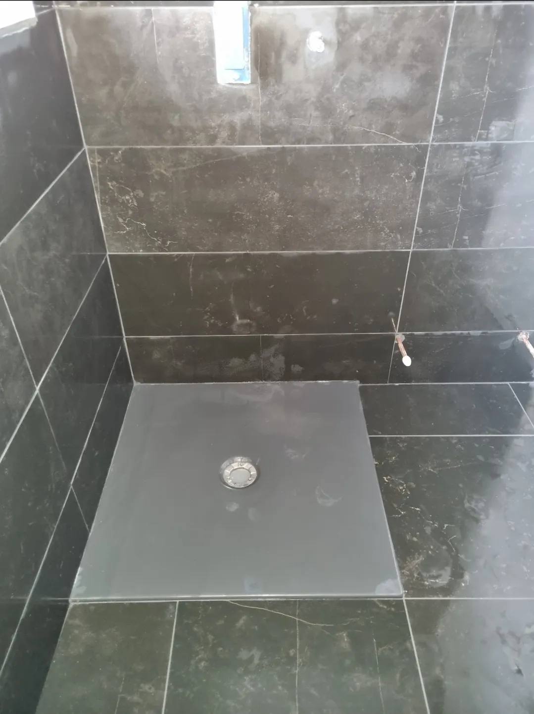 Bathroom black marble shower tray and drain close-up — bathroom tilers Surrey