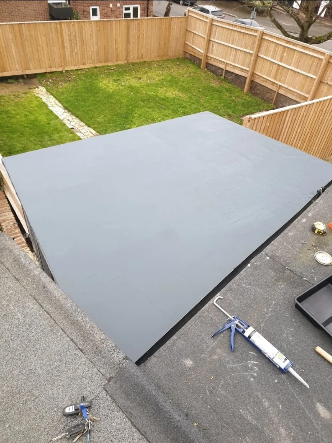 Grey GRP flat roof on outbuilding with garden and fence aerial view — flat roof contractors Surrey