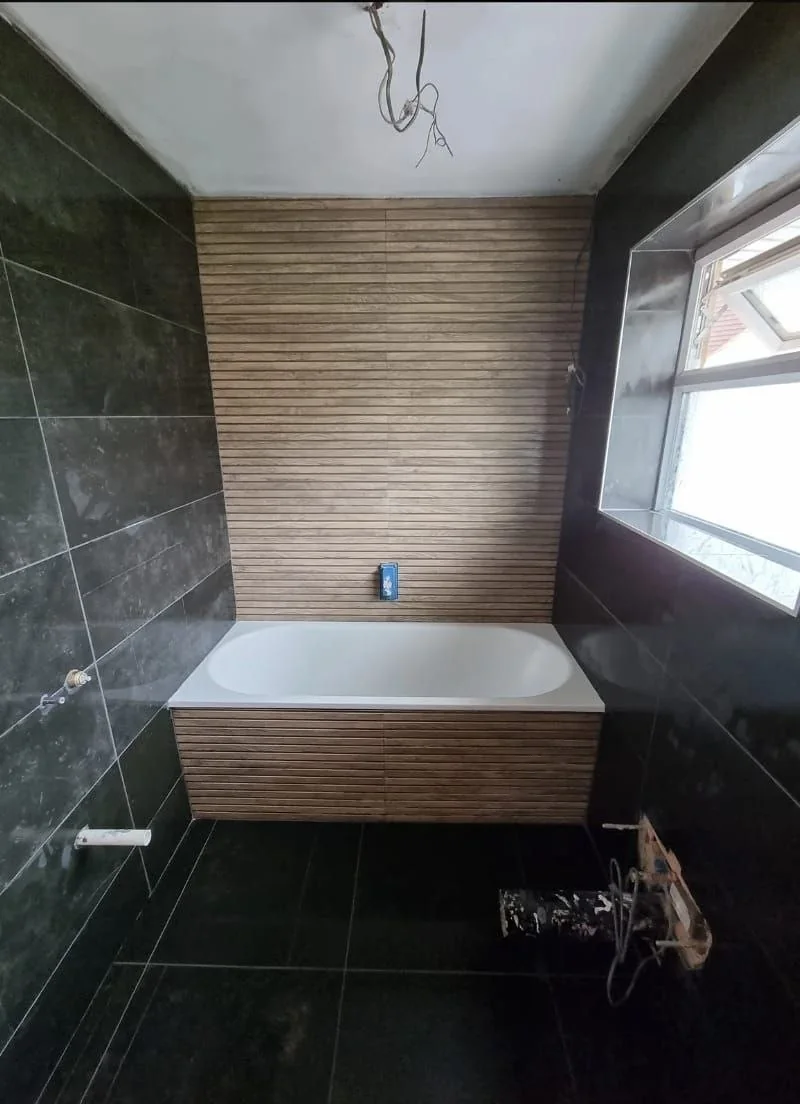 Luxury bathroom with dark marble tiles and wood panel bath — bathroom renovation Surrey